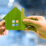 one hand exchanging a cardboard house with another hand, representing a financial gift.